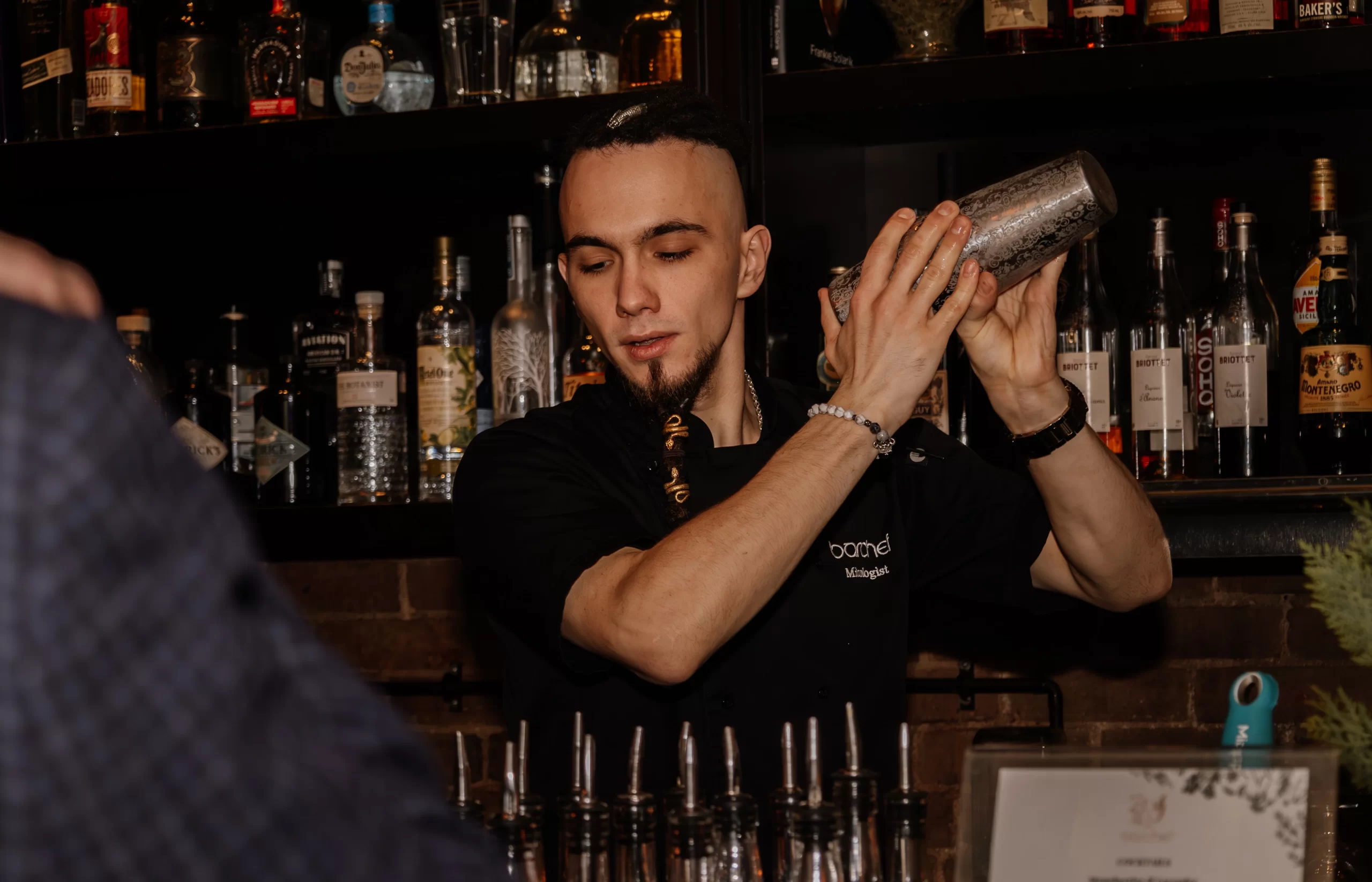 A bartender shaking a cocktail shaker behind the bar
